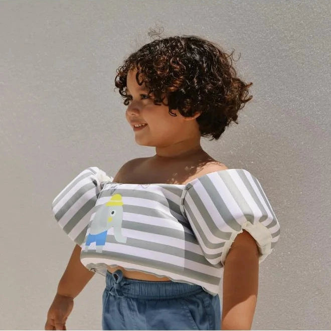 Child wearing a striped off-shoulder top with a plain background